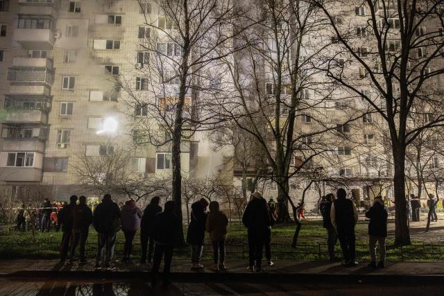 Residents look at smoke rising from a residential building that was damaged following a Russian drone attack on the city of Vyshhorod, in the Kyiv region early on November 30, 2025, amid the Russian invasion of Ukraine. A Russian drone attack has killed one person and wounded 11 on the outskirts of the Ukrainian capital, the regional governor said on November 30. (Photo by Roman PILIPEY / AFP)