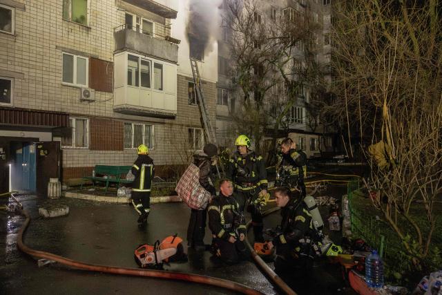 Firefighters take a break as smoke rises from a residential building that was set ablaze following a Russian drone attack on the city of Vyshhorod, in the Kyiv region early on November 30, 2025, amid the Russian invasion of Ukraine. A Russian drone attack has killed one person and wounded 11 on the outskirts of the Ukrainian capital, the regional governor said on November 30. (Photo by Roman PILIPEY / AFP)