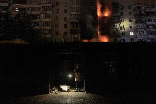 A person checks damages next to a residential building on fire following a Russian drone attack on the city of Vyshhorod, in the Kyiv region early on November 30, 2025, amid the Russian invasion of Ukraine. A Russian drone attack has killed one person and wounded 11 on the outskirts of the Ukrainian capital, the regional governor said on November 30. (Photo by Roman PILIPEY / AFP)