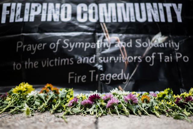 Flowers are placed for victims of the deadly November 26 fire as Philippine nationals in Hong Kong take part in a community prayer service at Tai Po, in Hong Kong’s Central district on November 30, 2025. An outpouring of grief swept Hong Kong on November 29, as thousands paid their respects and laid flowers for the 128 people killed in one of the city's deadliest fires, marking the start of an official three-day mourning period. (Photo by Philip FONG / AFP)