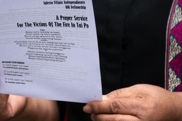 A Philippine national in Hong Kong holds a leaflet during a community prayer service for victims of the deadly November 26 fire in Tai Po, in Hong Kong’s Central district on November 30, 2025. An outpouring of grief swept Hong Kong on November 29, as thousands paid their respects and laid flowers for the 128 people killed in one of the city's deadliest fires, marking the start of an official three-day mourning period. (Photo by Philip FONG / AFP)