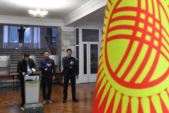 Members of a local electoral commission listen to the national anthem before the opening of a polling station during Kyrgyzstan's snap parliamentary elections in Bishkek on November 30, 2025. (Photo by Vyacheslav OSELEDKO / AFP)