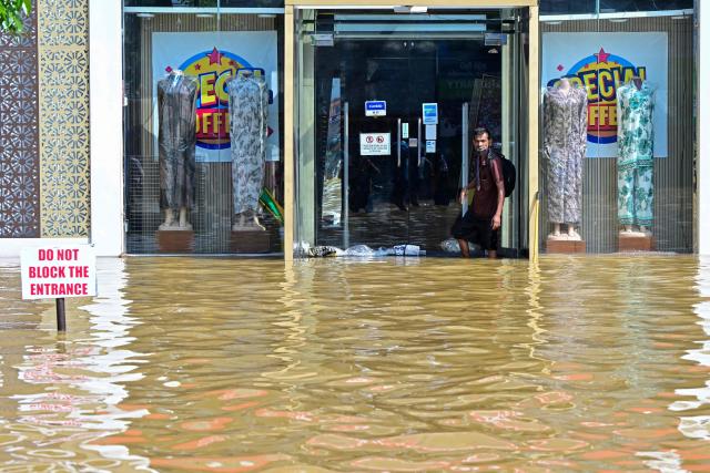 A man wades through a flooded road after heavy rainfall in Wellampitiya on the outskirts of Colombo on November 30, 2025. Sri Lankan authorities battled rising floodwaters in parts of the capital on November 30 after a powerful cyclone left a trail of destruction, killing at least 159 people across the country. (Photo by Ishara S. KODIKARA / AFP)