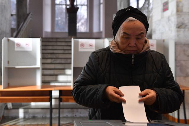 A woman casts her ballot at a polling station during Kyrgyzstan's snap parliamentary elections in Bishkek on November 30, 2025. (Photo by Vyacheslav OSELEDKO / AFP)