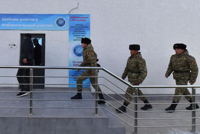 Kyrgyz servicemen arrive to vote at a polling station during Kyrgyzstan's snap parliamentary elections in the village of Tash-Dobo on November 30, 2025. (Photo by Vyacheslav OSELEDKO / AFP)