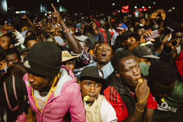 Fans dance and cheer as they follow performances during the 4th Nganya Awards celebrating matatu culture -Kenya’s iconic, privately owned public transport minibus- in Nairobi on November 29, 2025. The Nganya Awards is a celebration of Kenya’s matatu culture, honoring the matatu scene and the unique lifestyle around them. This years awards had over 40 categories, from matatu crews to vehicle designers, sound system and social influencers linked to the matatu lifestyle, with voting taking place ahead of the award show. (Photo by Fredrik LERNERYD / AFP)