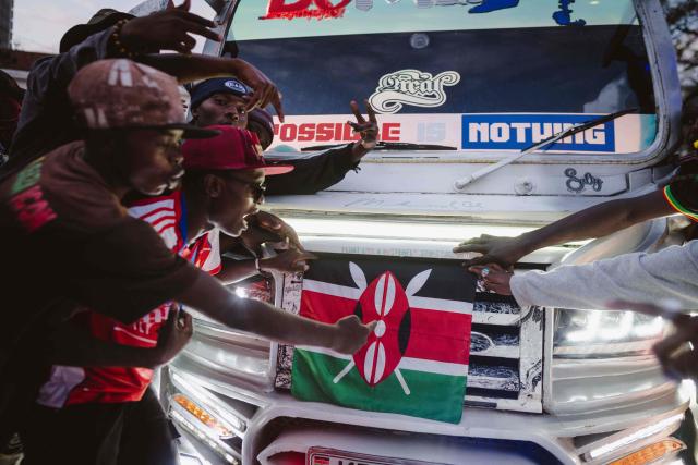 Fans holding a Kenyan flag gather around a matatu -Kenya’s iconic, privately owned public transport minibus- ahead of the 4th Nganya Awards in Nairobi on November 29, 2025. The Nganya Awards is a celebration of Kenya’s matatu culture, honoring the matatu scene and the unique lifestyle around them. This years awards had over 40 categories, from matatu crews to vehicle designers, sound system and social influencers linked to the matatu lifestyle, with voting taking place ahead of the award show. (Photo by Fredrik LERNERYD / AFP)