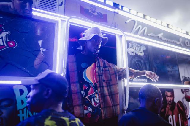 A conductor rides a matatu -Kenya’s iconic, privately owned public transport minibus- as fans gather during the 4th Nganya Awards in Nairobi on November 29, 2025. The Nganya Awards is a celebration of Kenya’s matatu culture, honoring the matatu scene and the unique lifestyle around them. This years awards had over 40 categories, from matatu crews to vehicle designers, sound system and social influencers linked to the matatu lifestyle, with voting taking place ahead of the award show. (Photo by Fredrik LERNERYD / AFP)
