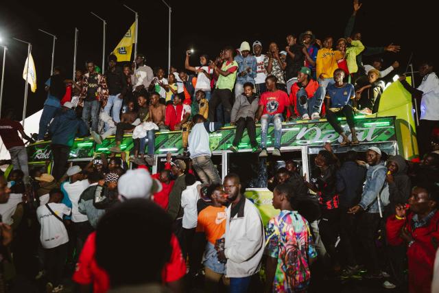 A group of fans rides atop a matatu -Kenya’s iconic, privately owned public transport minibus- driving around the venue as fans gather for the 4th Nganya Awards in Nairobi on November 29, 2025. The Nganya Awards is a celebration of Kenya’s matatu culture, honoring the matatu scene and the unique lifestyle around them. This years awards had over 40 categories, from matatu crews to vehicle designers, sound system and social influencers linked to the matatu lifestyle, with voting taking place ahead of the award show. (Photo by Fredrik LERNERYD / AFP)