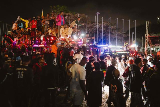 A group of fans rides atop a matatu -Kenya’s iconic, privately owned public transport minibus- driving around the venue as fans gather for the 4th Nganya Awards in Nairobi on November 29, 2025. The Nganya Awards is a celebration of Kenya’s matatu culture, honoring the matatu scene and the unique lifestyle around them. This years awards had over 40 categories, from matatu crews to vehicle designers, sound system and social influencers linked to the matatu lifestyle, with voting taking place ahead of the award show. (Photo by Fredrik LERNERYD / AFP)