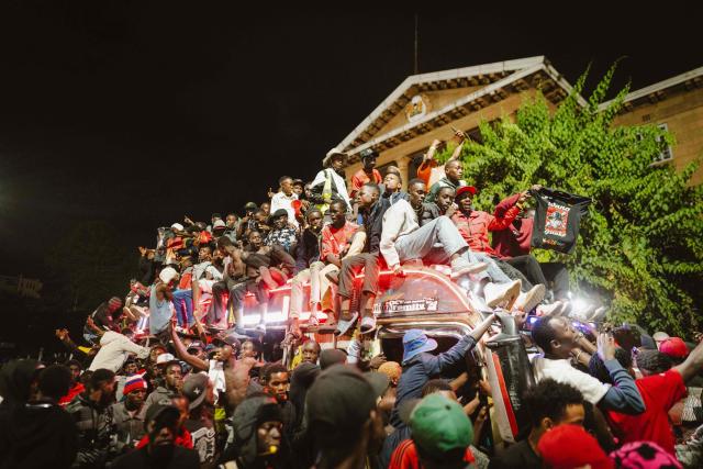 A group of fans rides atop a matatu -Kenya’s iconic, privately owned public transport minibus- driving around the venue as fans gather for the 4th Nganya Awards in Nairobi on November 29, 2025. The Nganya Awards is a celebration of Kenya’s matatu culture, honoring the matatu scene and the unique lifestyle around them. This years awards had over 40 categories, from matatu crews to vehicle designers, sound system and social influencers linked to the matatu lifestyle, with voting taking place ahead of the award show. (Photo by Fredrik LERNERYD / AFP)