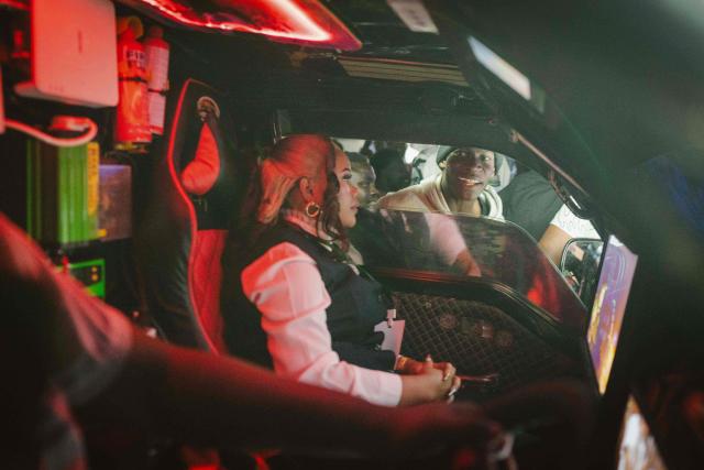 A fan looks through the window of a matatu -Kenya’s iconic, privately owned public transport minibus- admiring its interior as it circles the venue for the 4th Nganya Awards in Nairobi on November 29, 2025. The Nganya Awards is a celebration of Kenya’s matatu culture, honoring the matatu scene and the unique lifestyle around them. This years awards had over 40 categories, from matatu crews to vehicle designers, sound system and social influencers linked to the matatu lifestyle, with voting taking place ahead of the award show. (Photo by Fredrik LERNERYD / AFP)