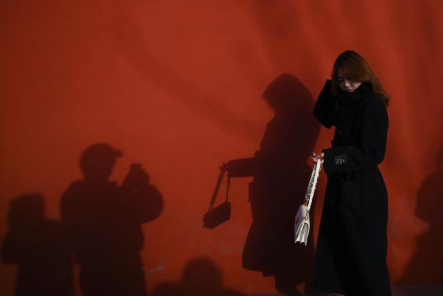 A woman poses for pictures in an area popular with tourists in Beijing on November 30, 2025. (Photo by Pedro PARDO / AFP)