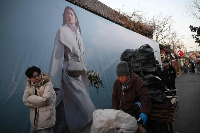 People walk in an area popular with tourists in Beijing on November 30, 2025. (Photo by Pedro PARDO / AFP)