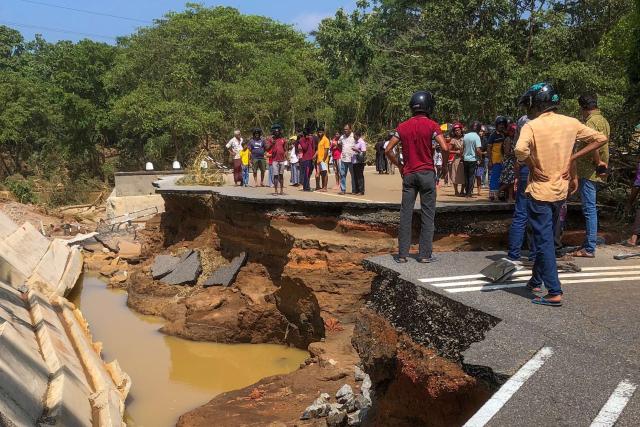 People gather around the Deduru Oya Bridge, which collapsed after floods in Kurunegala on November 30, 2025. Entire areas of Sri Lanka's capital were flooded on November 30 after a powerful cyclone triggered heavy rains and mudslides across the island, with authorities reporting nearly 200 dead and dozens more missing. (Photo by AFP)