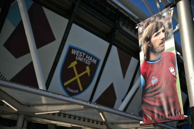 A photo of Billy Bonds hangs near to the stand named after him outside the stadium ahead of the English Premier League football match between West Ham United and Liverpool at the London Stadium, in London on November 30, 2025. Former West Ham captain and manager Billy Bonds has died at the age of 79, the club has announced today. (Photo by Ben STANSALL / AFP)