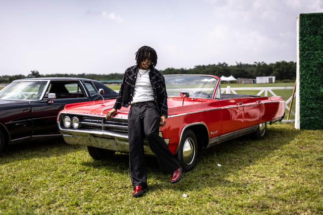 An attendee poses with a classic car exhibited during the Isimi Festival 2025 at the Isimi Wellness and Polo Country Estate in Epe, Lagos State, on November 29, 2025. (Photo by OLYMPIA DE MAISMONT / AFP)