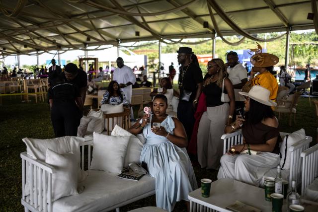 Spectators fan themselves as they gather during the Isimi Festival 2025 at the Isimi Wellness and Polo Country Estate in Epe, Lagos State, on November 29, 2025. (Photo by OLYMPIA DE MAISMONT / AFP)