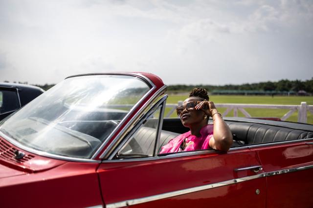 An attendee poses in a classic car exhibited during the Isimi Festival 2025 at the Isimi Wellness and Polo Country Estate in Epe, Lagos State, on November 29, 2025. (Photo by OLYMPIA DE MAISMONT / AFP)