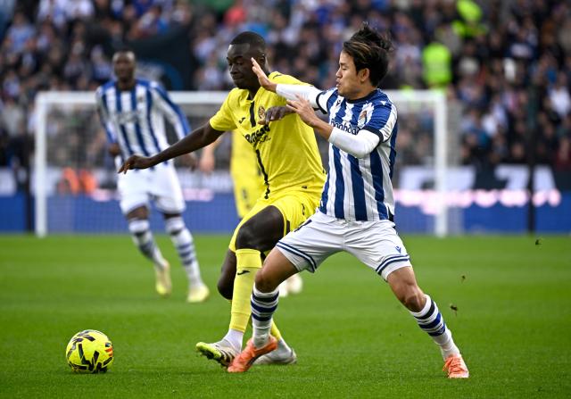 Villarreal's Senegalese midfielder #18 Pape Gueye fights for the ball with Real Sociedad's Japanese forward #14 Takefusa Kubo during the Spanish league football match between Real Sociedad and Villarreal CF at Anoeta Stadium in San Sebastian on November 30, 2025. (Photo by ANDER GILLENEA / AFP)