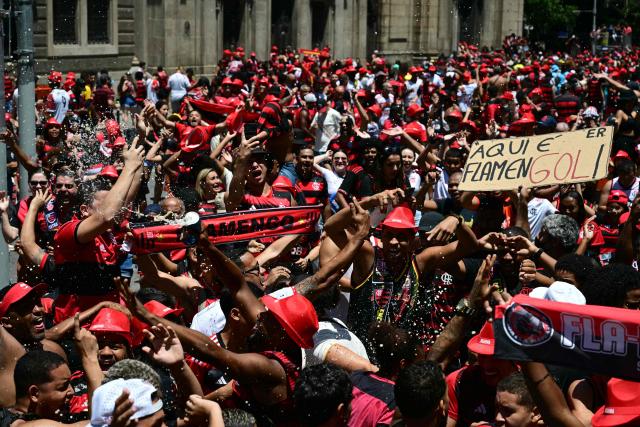 Flamengo supporters cheer as they gather in Rio de Janeiro, Brazil, on November 30, 2025, awaiting the arrival of their team a day after clinching the 2025 Copa Libertadores title. (Photo by Pablo PORCIUNCULA / AFP)