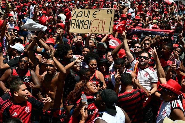Flamengo supporters cheer as they gather in Rio de Janeiro, Brazil, on November 30, 2025, awaiting the arrival of their team a day after clinching the 2025 Copa Libertadores title. (Photo by Pablo PORCIUNCULA / AFP)