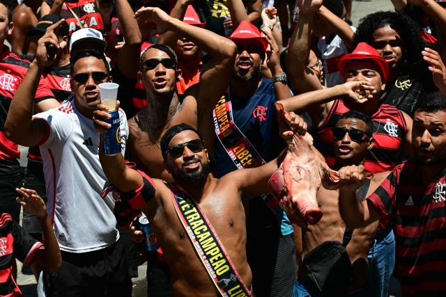 Flamengo supporters hold up a pig’s head (a jab at Palmeiras and its mascot) as they gather in Rio de Janeiro, Brazil, on November 30, 2025, waiting for their team to arrive a day after clinching the 2025 Copa Libertadores title. (Photo by Pablo PORCIUNCULA / AFP)