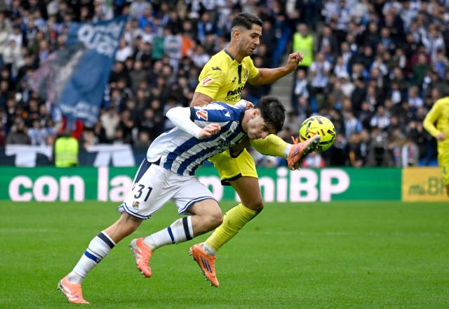 Real Sociedad's Spanish defender #31 Jon Martin fights for the ball with Villarreal's Spanish forward #22 Ayoze Perez Gutierrez during the Spanish league football match between Real Sociedad and Villarreal CF at Anoeta Stadium in San Sebastian on November 30, 2025. (Photo by ANDER GILLENEA / AFP)