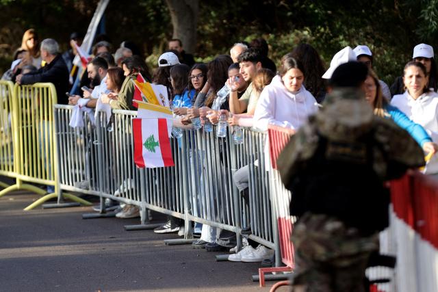 Holding the Lebanese flag, people wait for Pope Leo XIV in Beirut's eastern suburb of Hazmieh, where the he will drive past as he makes his way to the Presidential Palace on November 30, 2025. Pope Leo XIV wrapped up a four-day trip to Turkey on November 30, 2025, after a warm welcome by its tiny Christian community, before heading to Lebanon with a message of peace for the crisis-mired nation. (Photo by AFP)