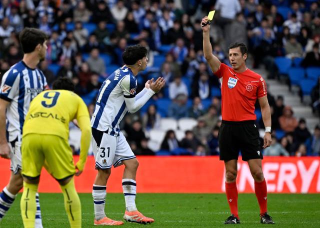 Spanish referee Cesar Soto Grado shows a yellow card to Real Sociedad's Spanish defender #31 Jon Martin during the Spanish league football match between Real Sociedad and Villarreal CF at Anoeta Stadium in San Sebastian on November 30, 2025. (Photo by ANDER GILLENEA / AFP)