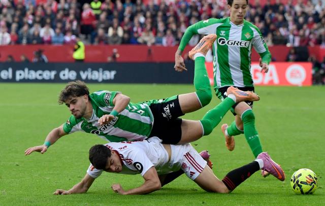 Real Betis' Moroccan forward #10 Abde Ezzalzouli and Sevilla's Spanish defender #16 Juanlu Sanchez fall during the Spanish league football match between Sevilla FC and Real Betis at Ramon Sanchez Pizjuan Stadium in Seville on November 30, 2025. (Photo by CRISTINA QUICLER / AFP)