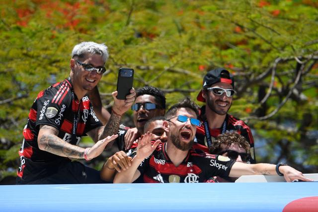 Brazil's Flamengo players celebrate as they leave on a bus the Galeao airport in Rio de Janeiro, Brazil, on November 30, 2025, a day after clinching the 2025 Copa Libertadores title. (Photo by Daniel RAMALHO / AFP)