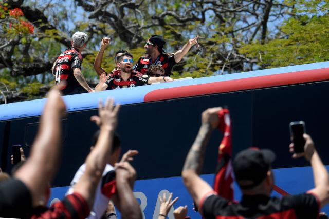 Flamengo players greet supporters as they leave on a bus the Galeao airport in Rio de Janeiro, Brazil, on November 30, 2025, a day after clinching the 2025 Copa Libertadores title. (Photo by Daniel RAMALHO / AFP)