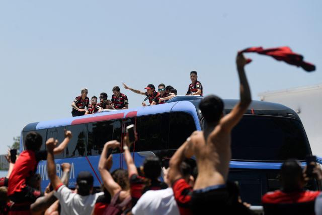 Flamengo players greet supporters as they leave on a bus the Galeao airport in Rio de Janeiro, Brazil, on November 30, 2025, a day after clinching the 2025 Copa Libertadores title. (Photo by Daniel RAMALHO / AFP)
