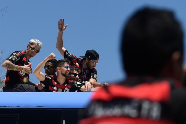 Brazil's Flamengo players celebrate as they leave on a bus the Galeao airport in Rio de Janeiro, Brazil, on November 30, 2025, a day after clinching the 2025 Copa Libertadores title. (Photo by Daniel RAMALHO / AFP)