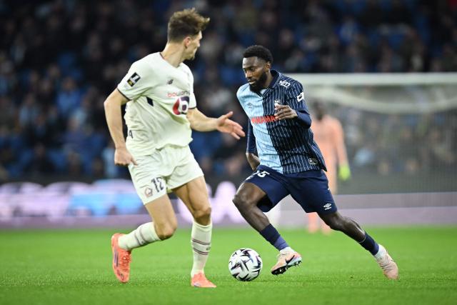 Lille's Belgian defender #12 Thomas Meunier (L) fights for the ball with Le Havre's Senegalese forward #45 Issa Soumare during the French L1 football match between Le Havre AC and Lille LOSC at the Oceane stadium in Le Havre, north-western France, on November 30, 2025. (Photo by Lou BENOIST / AFP)