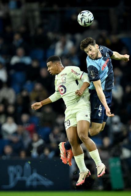 Lille's Moroccan forward #29 Hamza Igamane (L) fights for the ball with Le Havre's French defender #04 Gautier Lloris during the French L1 football match between Le Havre AC and Lille LOSC at the Oceane stadium in Le Havre, north-western France, on November 30, 2025. (Photo by Lou BENOIST / AFP)