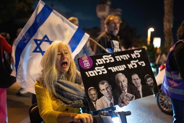 People chant slogans as they demonstrate outside the home of Israeli President Isaac Herzog in Tel Aviv following Prime minister Benjamin Netanyahu's request for a presidential pardon on November 30, 2025. Israeli Prime Minister Benjamin Netanyahu, on trial facing corruption charges, announced on November 30 he had submitted a pardon request, saying the long-running cases were tearing the country apart. US President Donald Trump wrote to Israeli President Isaac Herzog earlier this month, asking him to pardon Netanyahu, who has repeatedly denied wrongdoing in the proceedings. (Photo by Maya Levin / AFP)