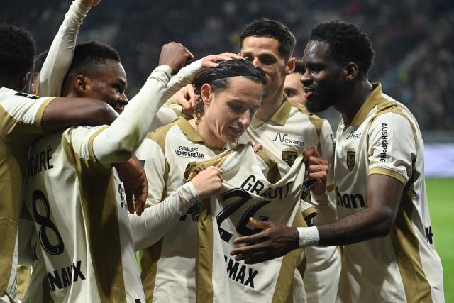 Lens' French forward #10 Florian Thauvin (C) celebrates with teammates as he holds Lens' French defender #24 Jonathan Gradit's jersey after scoring his team's second goal during the French L1 football match between SCO Angers and RC Lens at the Raymond-Kopa stadium in Angers on November 30, 2025. (Photo by JEAN-FRANCOIS MONIER / AFP)