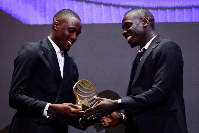 Botswana's sprinter Letsile Tebogo (L) gives 
Men’s track athlete of the year award to Kenya's world 800m champion Emmanuel Wanyonyi (R) on stage during the World Athletics Awards 2025 in Monaco, on November 30, 2025. (Photo by Valery HACHE / AFP)
