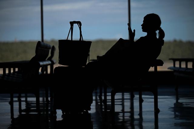 A woman waits by a boarding gate at the Simon Bolivar International Airport in Maiquetia, La Guaira State, Venezuela, on November 30, 2025. US President Donald Trump sharply escalated his threats against Venezuela on Saturday with an ominous warning that the country's airspace should be considered "closed," raising fears of imminent military action. (Photo by Federico PARRA / AFP)