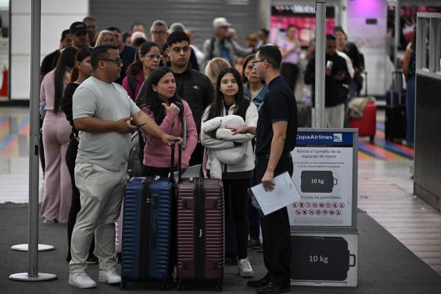 Passengers queue at a counter at the Simon Bolivar International Airport in Maiquetia, La Guaira State, Venezuela, on November 30, 2025. US President Donald Trump sharply escalated his threats against Venezuela on Saturday with an ominous warning that the country's airspace should be considered "closed," raising fears of imminent military action. (Photo by Federico PARRA / AFP)