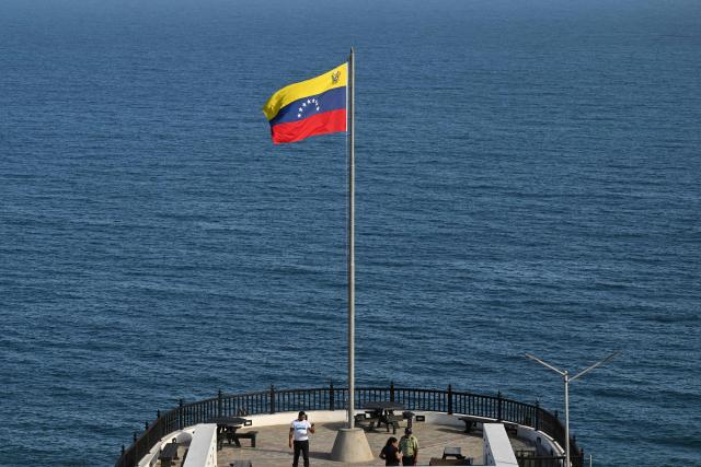 People visit the viewpoint of Fortin del Vigia in Maiquetia, La Guaira State, Venezuela, on November 30, 2025. US President Donald Trump sharply escalated his threats against Venezuela on Saturday with an ominous warning that the country's airspace should be considered "closed," raising fears of imminent military action. (Photo by Federico PARRA / AFP)