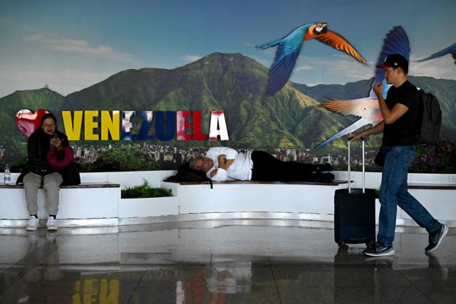 People rest near a boarding gate at the Simon Bolivar International Airport in Maiquetia, La Guaira State, Venezuela, on November 30, 2025. US President Donald Trump sharply escalated his threats against Venezuela on Saturday with an ominous warning that the country's airspace should be considered "closed," raising fears of imminent military action. (Photo by Federico PARRA / AFP)