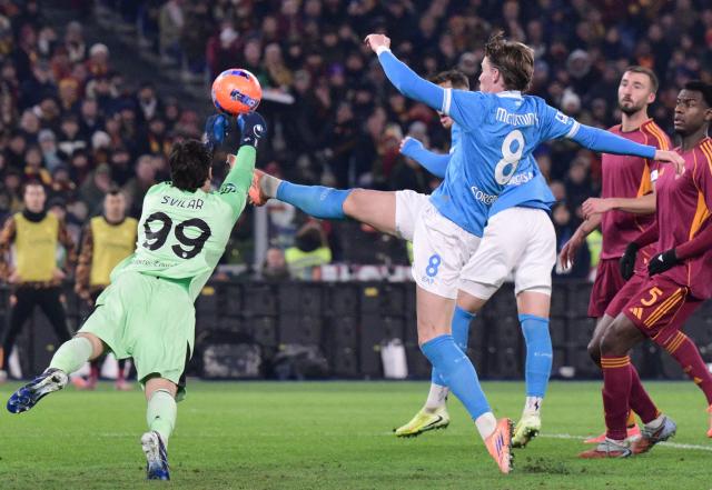TOPSHOT - Roma's Serbian goalkeeper #99 Mile Svilar dives to make a save on Napoli's Scottish midfielder #08 Scott McTominay during the Italian Serie A football match between AS Roma and Napoli at the Olympic Stadium in Rome on November 30, 2025. (Photo by Tiziana FABI / AFP)