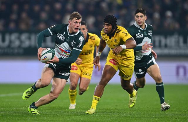 Pau's French centre Emilien Gailleton (L) runs with the ball during the French Top 14 rugby union match between Section Paloise Bearn Pyrenees (Pau) and Stade Rochelais (La Rochelle) at Stade du Hameau in Pau, south-western France on November 30, 2025. (Photo by Gaizka IROZ / AFP)