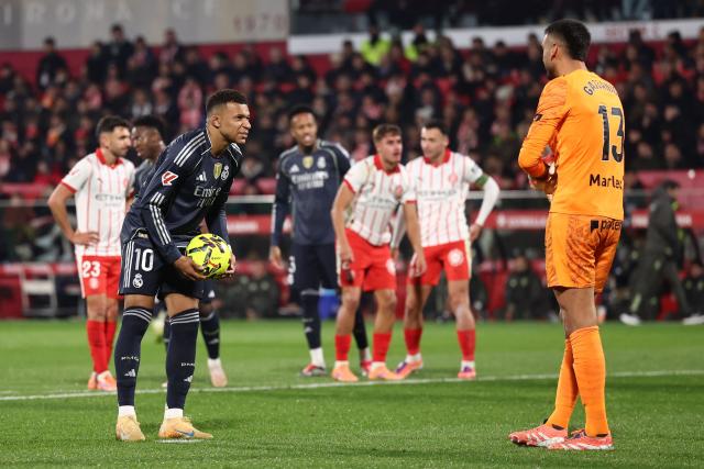 Real Madrid's French forward #10 Kylian Mbappe speaks with Girona's Argentine goalkeeper #13 Paulo Gazzaniga prior to shooting a penalty kick during the Spanish league football match between Girona FC and Real Madrid CF at Montilivi Stadium in Girona on November 30, 2025. (Photo by Josep LAGO / AFP)
