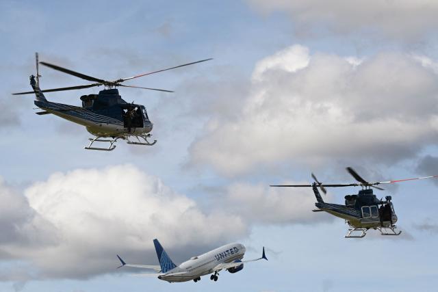 An United Airlines plane takes off in front of two helicopters of the Guatemalan Army during 'Open base 2025' at the Guatemalan Air Force Base in Guatemala City on November 30, 2025. (Photo by Johan ORDONEZ / AFP)