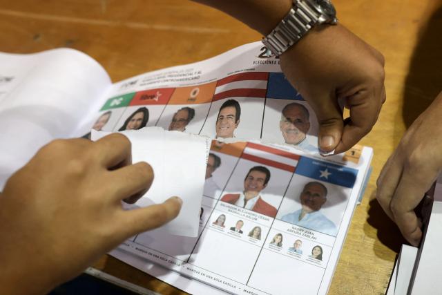 An election official rips an unmarked ballot after the closing of the polling stations during Honduras' general election in Tegucigalpa on November 30, 2025. Hondurans voted for president on November 30, 2025, amid threats by US President Donald Trump to cut aid to the country if his preferred candidate loses. (Photo by Lucas AGUAYO / AFP)