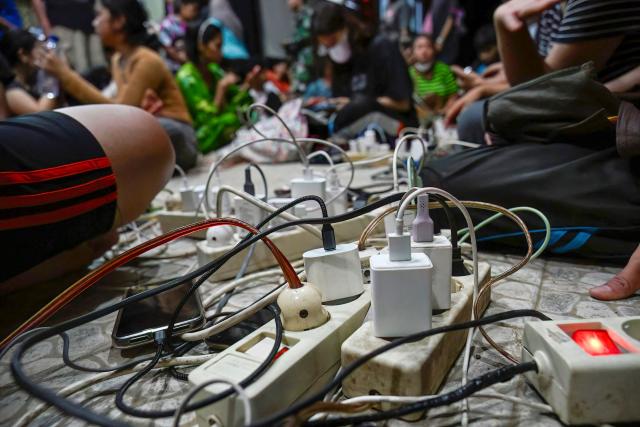 Charging blocks for mobile phones are seen as displaced residents rest in a shelter following flash floods and landslides in Pandan in Central Tapanuli, Indonesia's North Sumatra province on November 30, 2025. The death toll from floods that hit Indonesia this week has risen to more than 300 people, according to figures from the disaster agency on November 29. (Photo by YT Hariono / AFP)